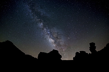 The Milky Way arches high in the night sky above Roques de Garcia in Teide National Park, UNESCO World Heritage Site, Tenerife, Canary Islands, Spain, Europe