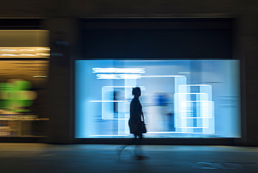 Pedestrian in a rush in the city walking at night on Oxford Street, London, England, United Kingdom, Europe