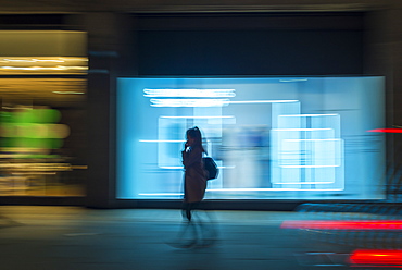 Pedestrian in a rush in the city walking at night on Oxford Street, London, England, United Kingdom, Europe