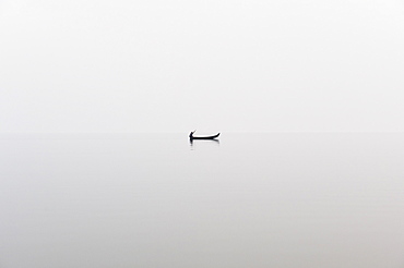 A fishing boat on a perfectly calm Indawgyi Lake in northern Myanmar on a misty afternoon, Myanmar (Burma), Asia