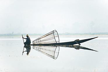 A basket fisherman on Inle Lake scans the still and shallow water for signs of life, Myanmar (Burma), Asia