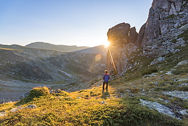 The last rays of sun disappear behind a rock face after a day of trekking in the Rila Mountains, Bulgaria, Europe