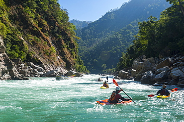 Kayakers negotiate their way through whitewater rapids on the Karnali River in west Nepal, Asia