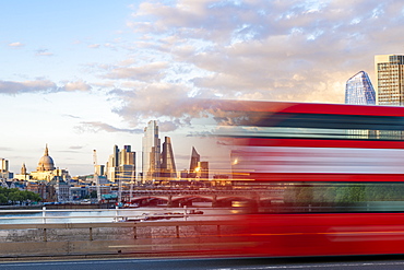 A red London bus goes past in a blur across Waterloo Bridge with the City of London and Southbank in distance, London, England, United Kingdom, Europe