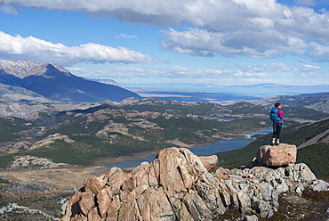 A woman takes a break from hiking the trail in El Chalten National Park to take in the view, Lake Vied, Patagonia, Argentina, South America