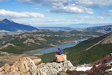 A woman takes a break from hiking the trail in El Chalten National Park to take in the view, Lake Vied, Patagonia, Argentina, South America