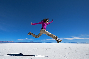 A girl leaps into the air at the Salinas Grandes (salt flats) near Purmamarca, Argentina, South America