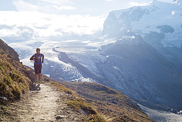 Running a trail in the Swiss Alps near Zermatt with a view of Monte Rosa in the distance, Zermatt, Valais, Switzerland, Europe