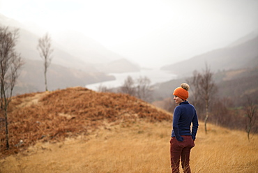 A woman walking near Kinlochlevan with a misty view towards Loch Leven, Perth and Kinross, Highlands, Scotland, United Kingdom, Europe