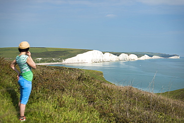 A woman looks towards the Seven Sisters while walking the South Downs Way, South Downs National Park, East Sussex, England, United Kingdom, Europe