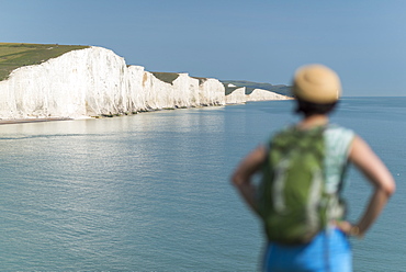 A woman looks towards the Seven Sisters while walking the South Downs Way, South Downs National Park, East Sussex, England, United Kingdom, Europe