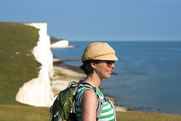 A woman looks out over the cliffs near Beachy Head with views of the Seven Sisters coastline, South Downs National Park, East Sussex, England, United Kingdom, Europe