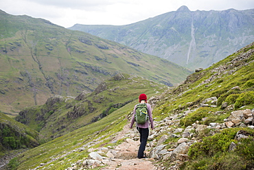 A woman walking down into Great Langdale from Crinkle Craggs with a view of Stickle Pike in the distance, Lake District National Park, Cumbria, England, United Kingdom, Europe