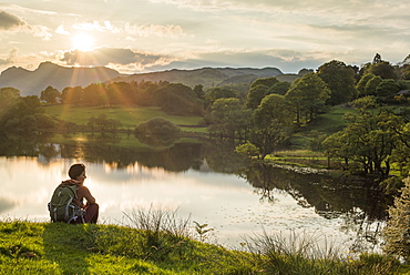 A woman looks out over Loughrigg Tarn near Ambleside, Lake District National Park, Cumbria, England, United Kingdom, Europe