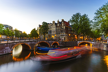 Keizergracht Canal at dusk, trailing light blur from a tourist boat, Amsterdam, North Holland, The Netherlands, Europe