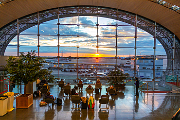 Passengers viewing sunset at Charles de Gaulle airport departure lounge, Terminal 2F, Paris, France, Europe