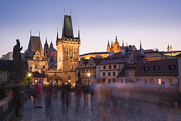 Charles Bridge, Lesser Towers, and Prague Castle at night with blurred pedestrians, UNESCO World Heritage Site, Prague, Czech Republic, Europe