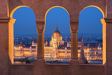 Hungarian Parliament at night, viewed from the columns and windows of the Fisherman's Bastion, UNESCO World Heritage Site, Budapest, Hungary, Europe