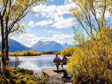 Couple on a bench looking out over Lake Wakatipu, Otago Region, South Island, New Zealand, Pacific