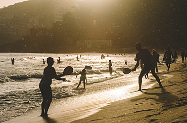 People play racquetball on the beach in Leblon, at sunset with a light drizzle, Rio de Janeiro, Brazil, South America