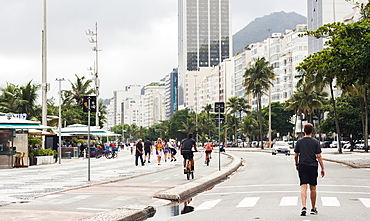 Young man walks on street adjacent the boardwalk at Copacabana Beach, Rio de Janeiro, Brazil, South America