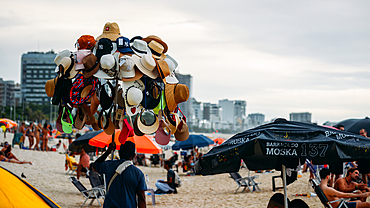 Salesman displaying hats for sale, at Leblon beach in Rio de Janeiro, Brazil, South America