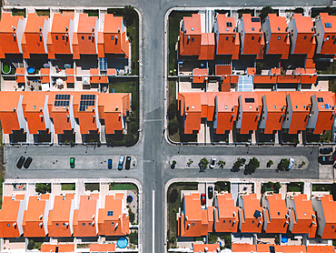 Overhead aerial drone shot showcasing a well-planned suburban area featuring red-tiled homes and organised streets