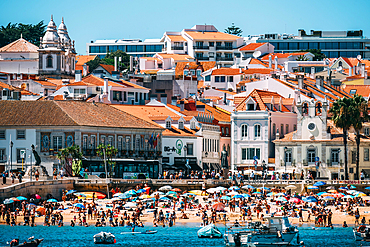 Visitors enjoy a sunny day on the beach in Cascais, surrounded by colorful umbrellas and historic buildings, Portuguese Riviera, Cascais, 30km west of Lisbon, Portugal, Europe