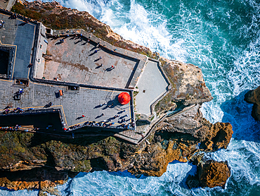 Aerial drone top down view of Nazare lighthouse, Portugal with waves crashing on the rocks underneath