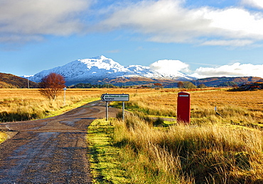 Winter view of a red telephone box and road toward snow covered Beinn Resipol mountain in the moors of the Scottish Highlands, Scotland, United Kingdom, Europe