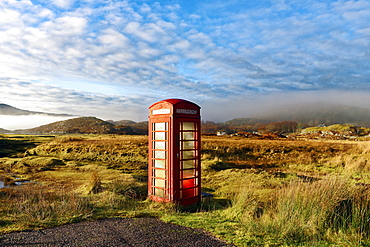 Autumn view of a red telephone box at the side of a quiet road in the remote misty Ardnamurchan moors of the Scottish Highlands, Scotland, United Kingdom, Europe