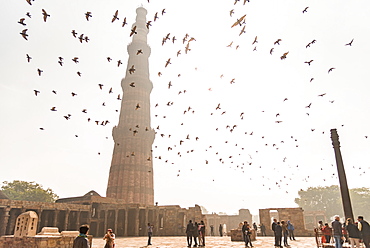 Birds fly over visitors while they take photos of one another at Qutub Minar, UNESCO World Heritage Site, New Delhi, India, Asia