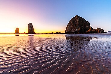 Haystack Rock and The Needles at sunset, with textured sand in the foreground, Cannon Beach, Clatsop county, Oregon, United States of America, North America