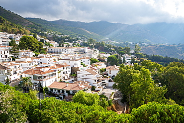 Sun rays burst through the clouds over the white washed buildings of Mijas Pueblo, Andalusia, Spain, Europe