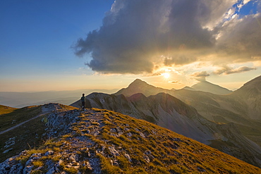 Hiker in front of mountain Portella at sunset, Gran Sasso e Monti della Laga National Park, Abruzzo, Italy, Europe