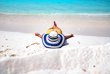 woman with straw hat sunbathing on tropical beach