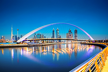 Colorful sunset over Dubai Downtown skyscrapers and the newly built Tolerance bridge as viewed from the Dubai water canal.