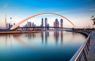 Colorful sunset over Dubai Downtown skyscrapers and the newly built Tolerance bridge as viewed from the Dubai water canal.