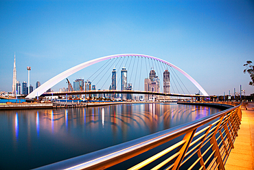 Colorful sunset over Dubai Downtown skyscrapers and the newly built Tolerance bridge as viewed from the Dubai water canal.