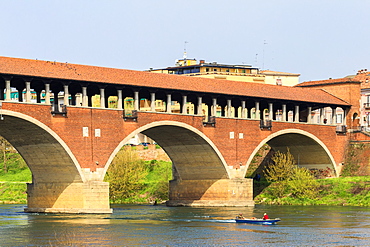 A boat navigates under the Ponte Coperto, Pavia, Pavia province, Lombardy, Italy, Europe