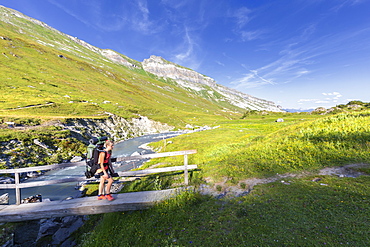 Woman hiker runs across a footbridge, Unterer Segnesboden, Flims, District of Imboden, Canton of Grisons (Graubunden), Switzerland, Europe