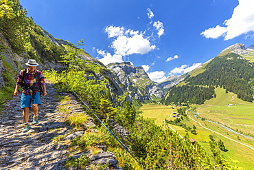 A hiker walks along the path called Scala Mola, Val Bargis valley, Flims, District of Imboden, Canton of Grisons (Graubunden), Switzerland, Europe