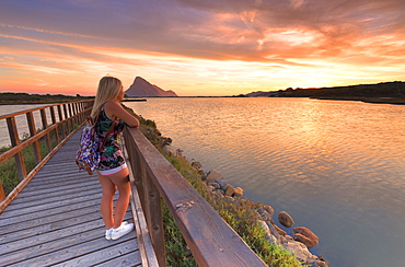 A girl looks at sunrise from a walkway, Porto Taverna, Loiri Porto San Paolo, Olbia Tempio province, Sardinia, Italy, Mediterranean, Europe