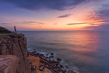 A girl looks at sunset from a cliff, Sant'Antioco Island, Sud Sardegna province, Sardinia, Italy, Mediterranean, Europe