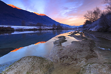 The colors of sunset are reflected in the Adda River, Valtellina, Lombardy, Italy, Europe