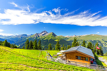 Alpine hut with Swiss flag beneath stunning clouds, Urses, Surselva, Graubunden, Switzerland, Europe