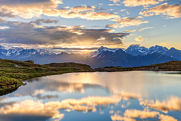 The sun and clouds is reflected in the Arcoglio Lake at sunrise, Valmalenco, Valtellina, Lombardy, Italy, Europe