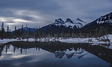 Canadian Rockies on a gloomy day, showing The Three Sisters over lake reflection, Alberta, Canada, North America