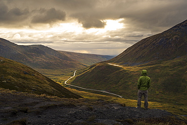 Lone hiker looking at mountain landscape at sunset, Alaska, United States of America, North America