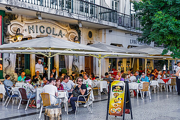 Historic Cafe Nicola entrance with art deco facade and seated customers at outdoor tables in Rossio Square, Lisbon, Portugal, Europe